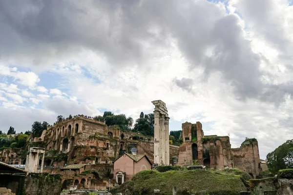 A római Forum Romanum romjai, zöldellő növényzet és felhős égbolt alatt.
