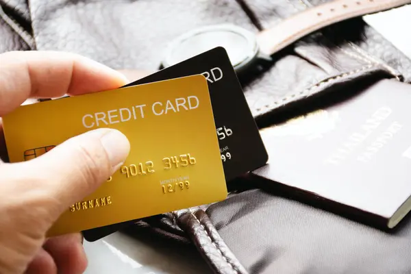 Két bankkártya és egy útlevél látható egy utazótáska mellett, készülve a külföldi utazásra.