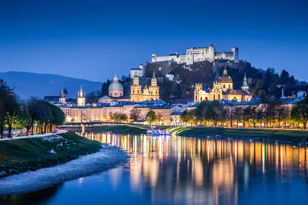 Salzburg városának esti panorámája a Hohensalzburg várral és a Salzach folyóval.