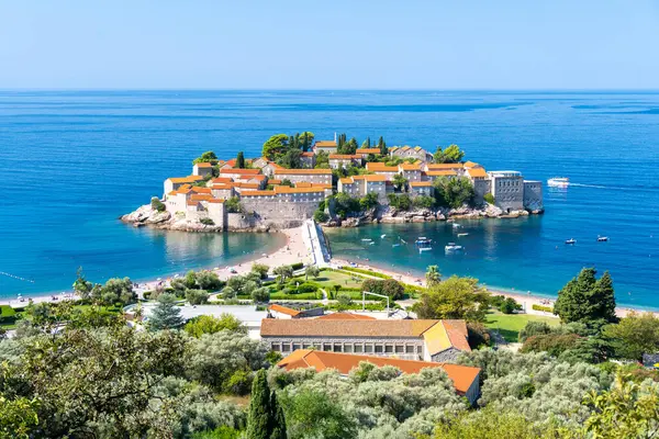 Sveti Stefan szigete Montenegróban, gyönyörű tengerparttal és zöld növényzettel.