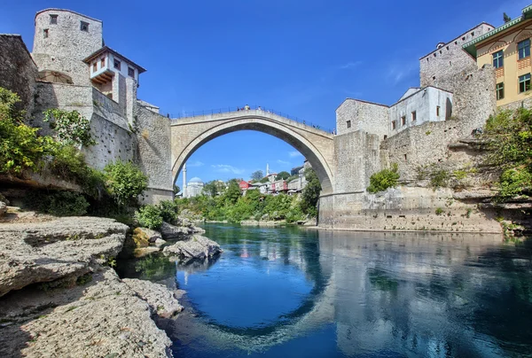 A Mostar hídja, a Neretva folyó felett ívelve, gyönyörű környezetben.