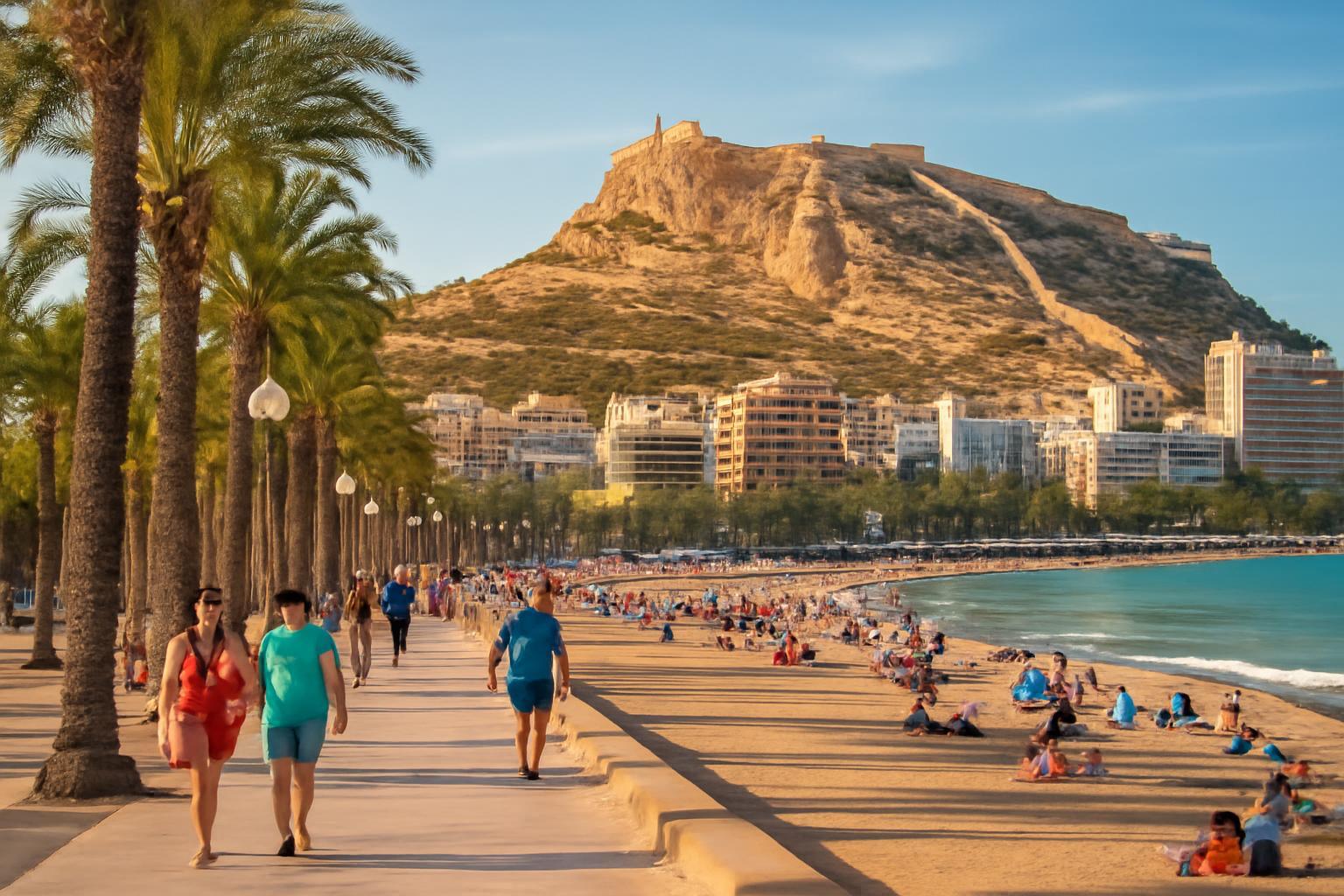 Alicante tengerpartja, pálmafák és emberek sétálnak a sétányon.