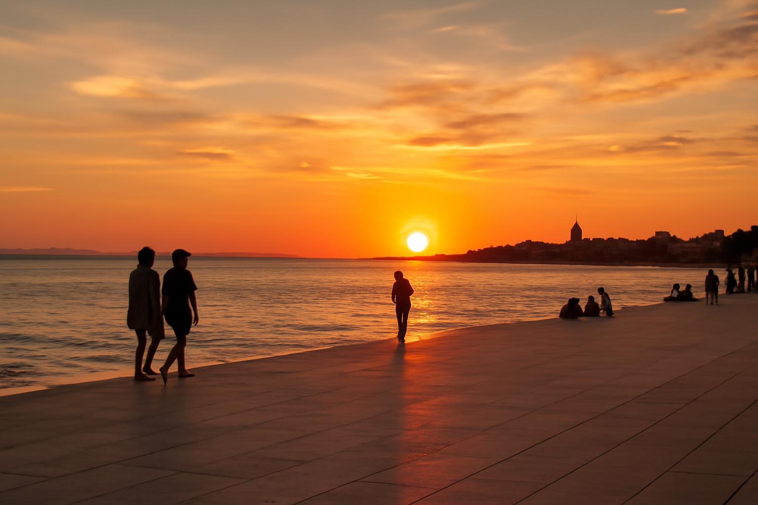 Zadar partján sétáló emberek a naplementében, gyönyörű színekben.